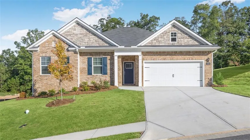 Brick and stone exterior with a two-car garage, front entry door, and manicured landscaping
