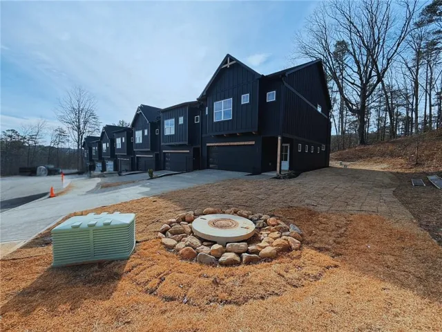 View of side of property featuring an attached garage, board and batten siding, concrete driveway, and a residential view