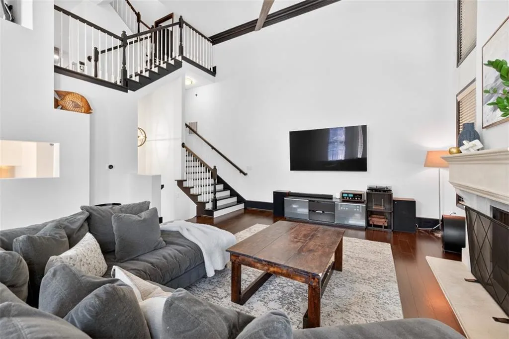 Living room with a towering ceiling, a fireplace with raised hearth, hardwood / wood-style floors, and stairs