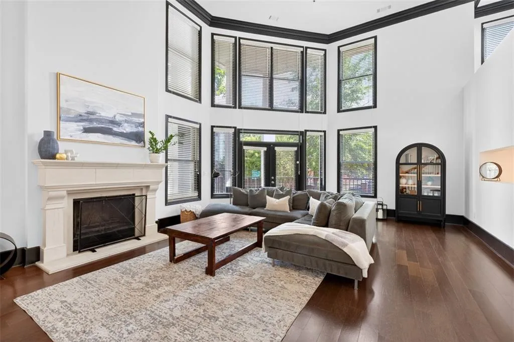 Living room with ornamental molding, healthy amount of natural light, a premium fireplace, dark wood-style floors, and a towering ceiling
