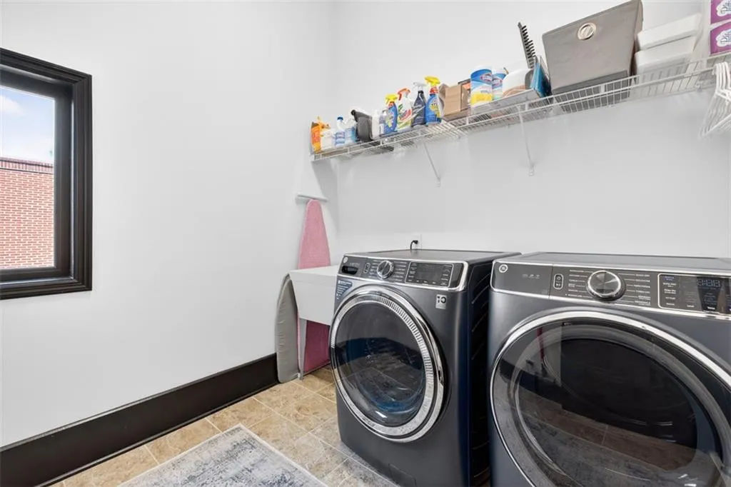 Laundry room with washing machine and clothes dryer and light tile patterned flooring
