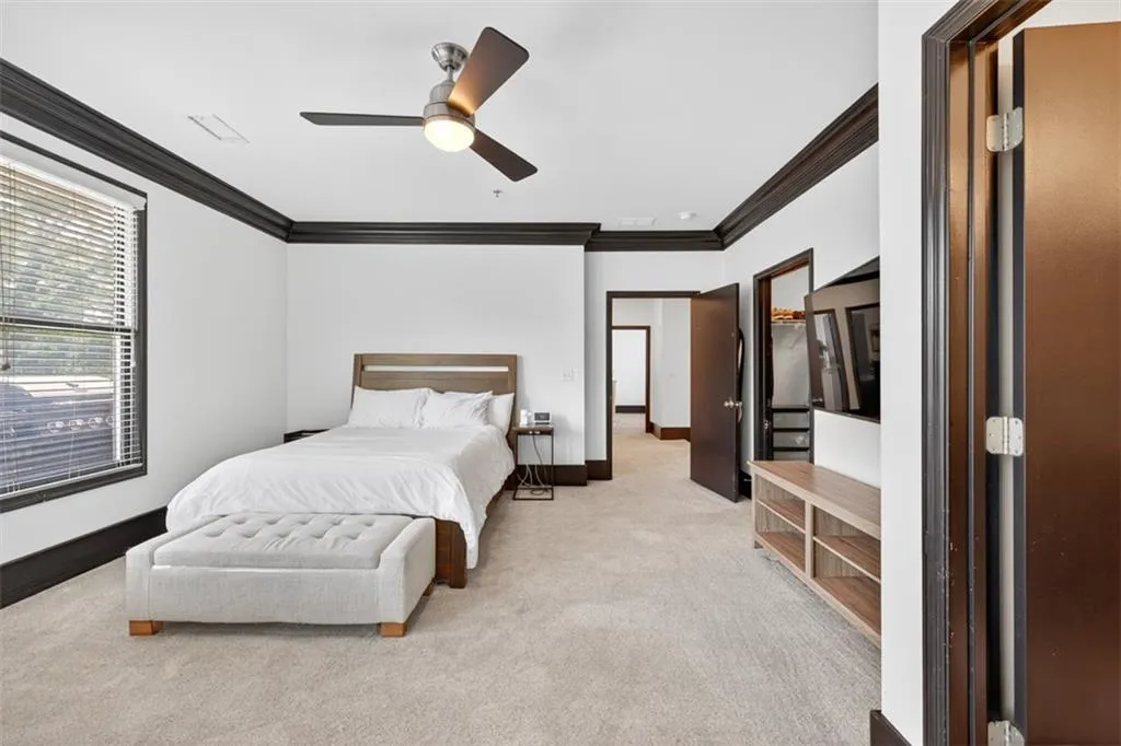 Bedroom with ornamental molding, light colored carpet, and ceiling fan