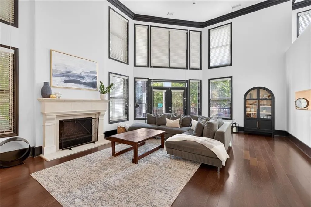 Living area with a high end fireplace, dark wood-type flooring, crown molding, and a towering ceiling