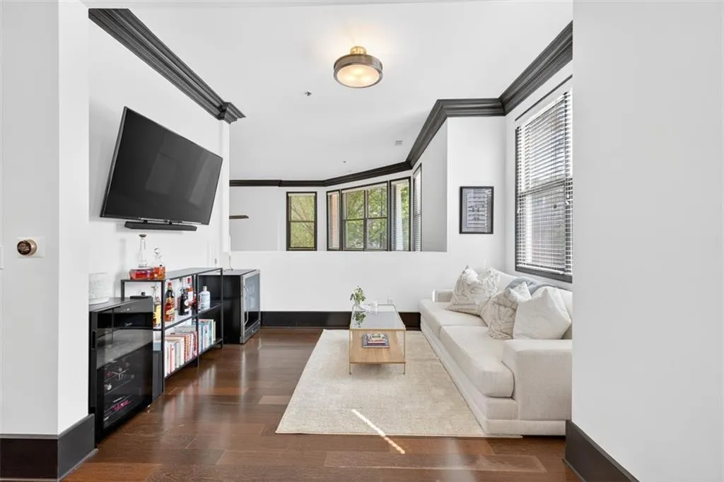 Living area with ornamental molding, a bar, and dark wood-style floors