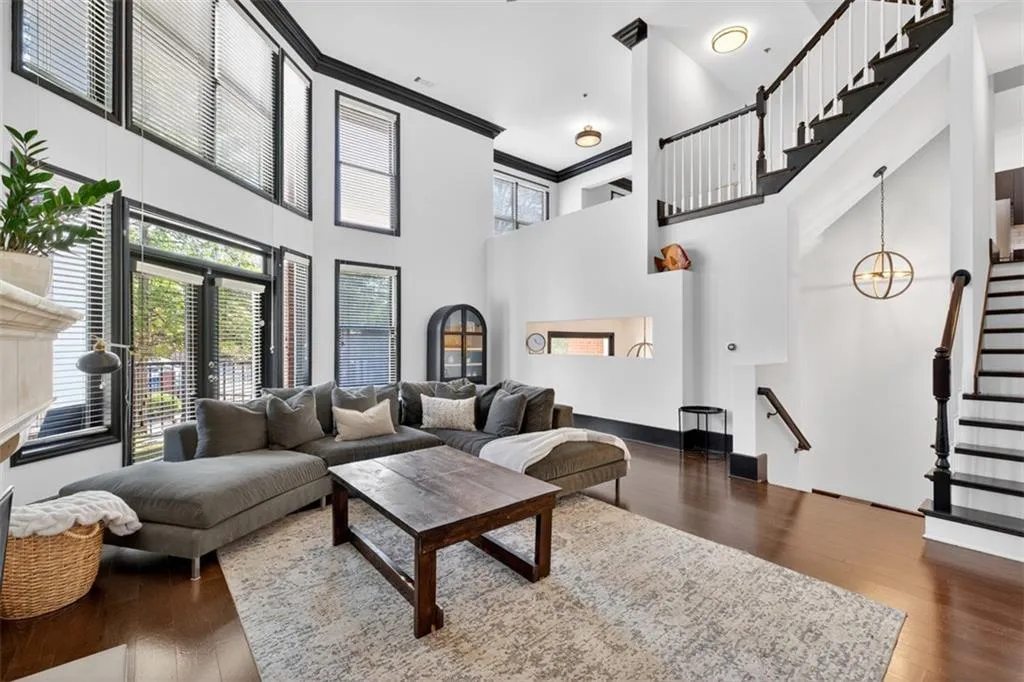 Living area featuring a towering ceiling, crown molding, dark wood-type flooring, and stairway