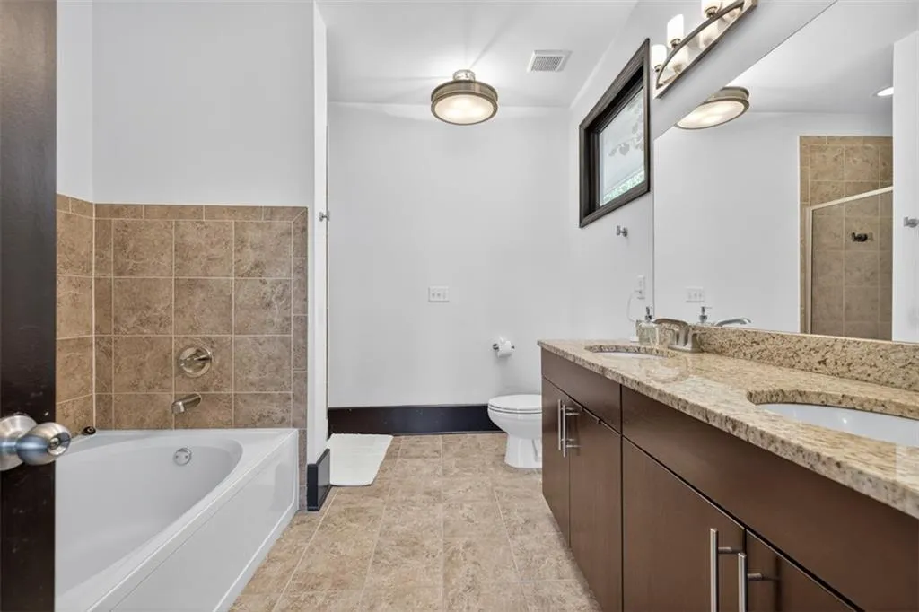 Full bath featuring a bath, double vanity, a stall shower, and light tile patterned floors