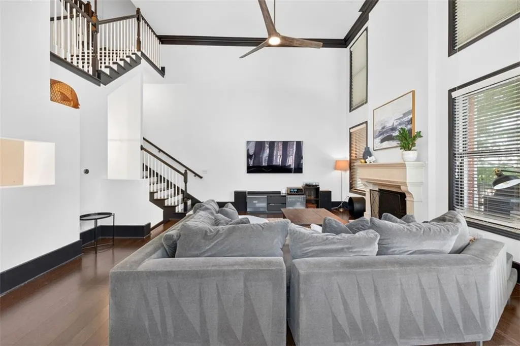 Living room featuring a high ceiling, dark wood-type flooring, a fireplace, stairs, and crown molding