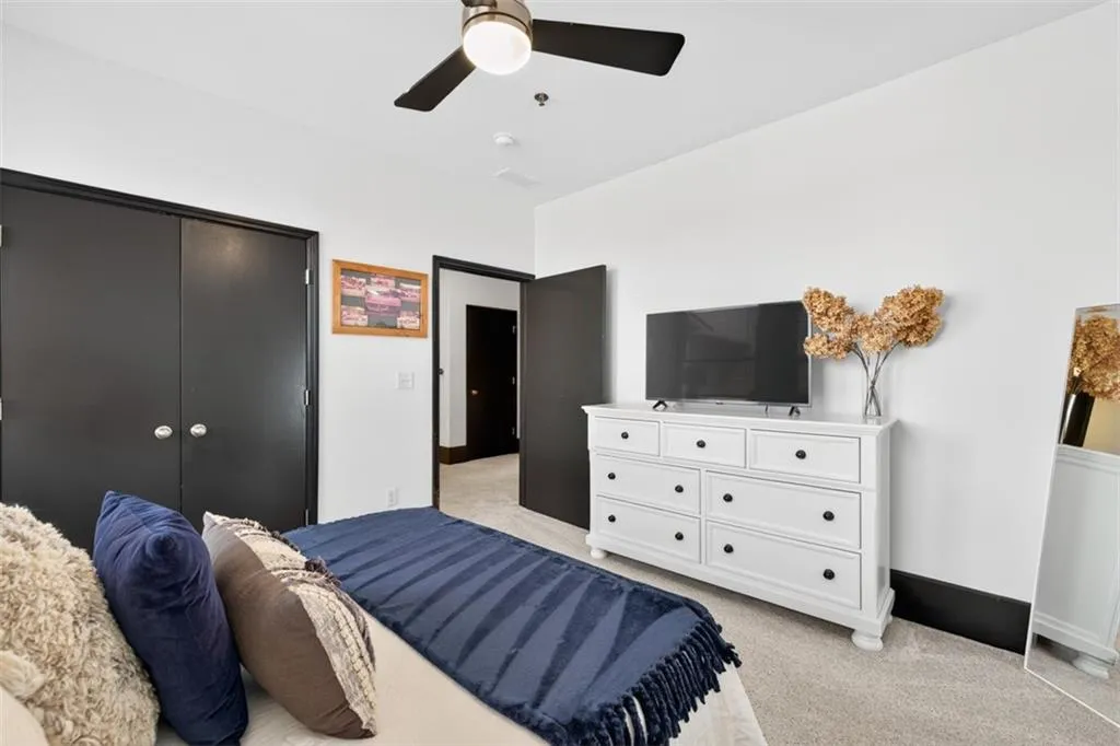 Bedroom featuring light colored carpet, a closet, and a ceiling fan
