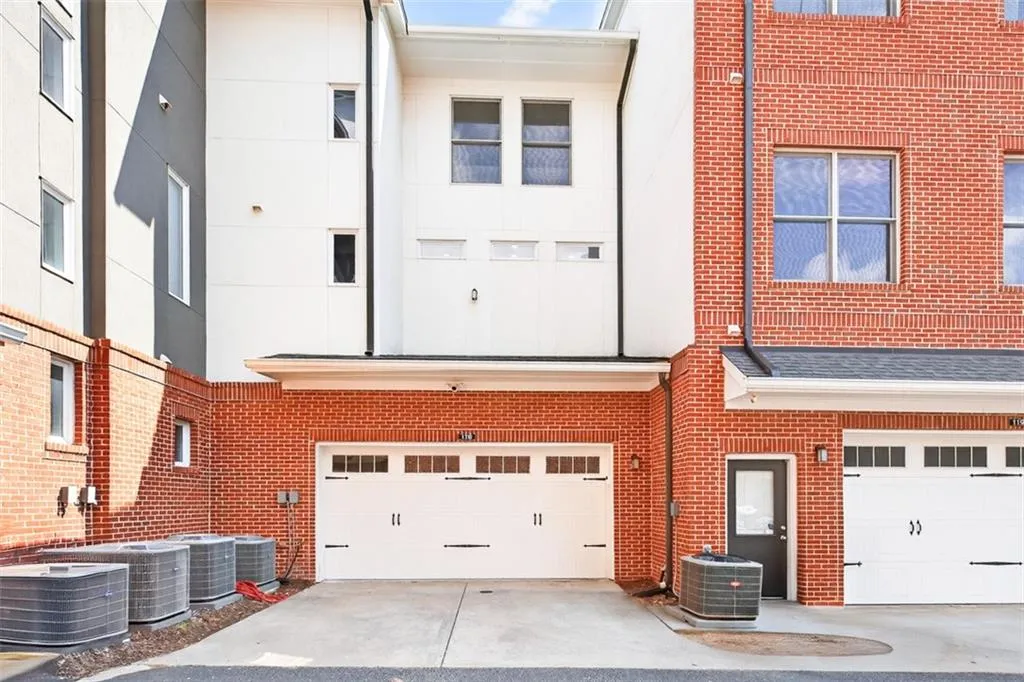 Back of house with brick siding, concrete driveway, and a garage