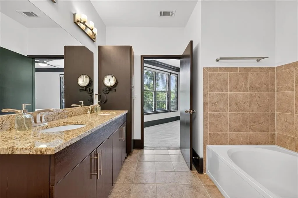 Bathroom featuring double vanity, a garden tub, and light tile patterned flooring