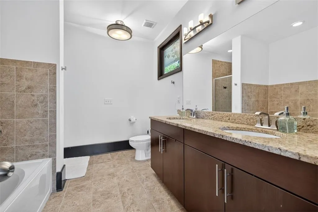 Full bathroom with double vanity, tile walls, a stall shower, a bath, and light tile patterned floors