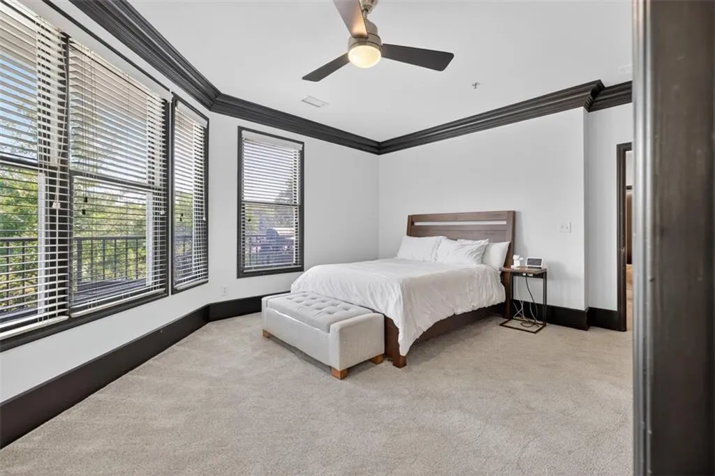 Bedroom with light colored carpet, crown molding, and ceiling fan