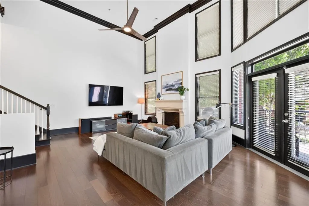 Living room with a fireplace, dark wood-style floors, stairway, a towering ceiling, and ceiling fan