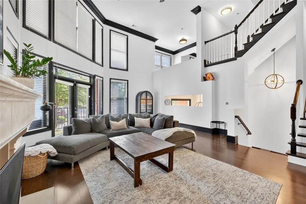 Living room with a towering ceiling, dark wood finished floors, and ornamental molding