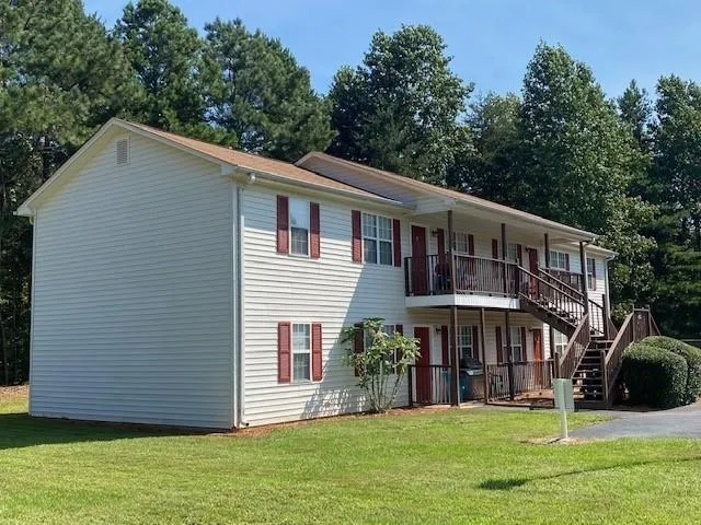 Two-story structure with white siding and a brown shingle roof