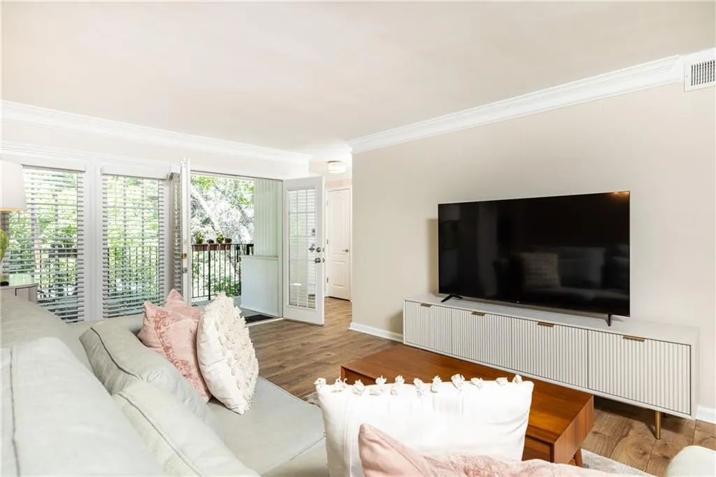 Living area featuring wood-finish flooring, crown molding, and direct access to an outdoor balcony