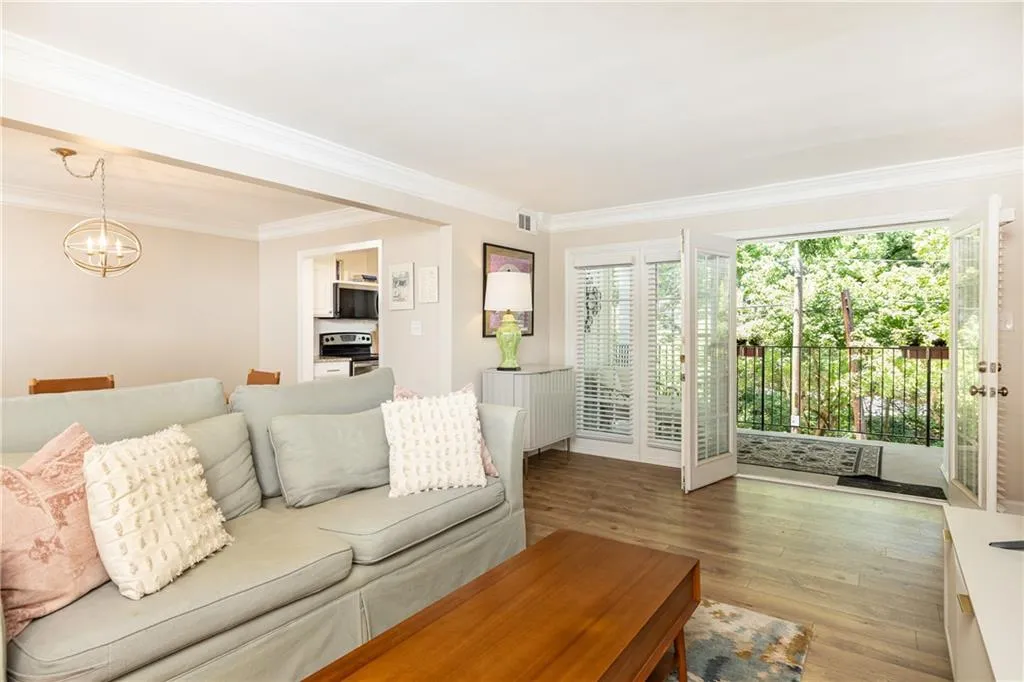 Living area featuring wood-finish flooring, crown molding, and direct access to an outdoor balcony