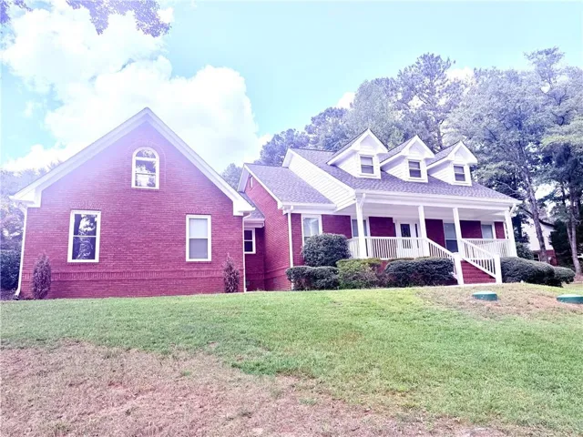 Brick exterior, covered front porch, white railings, dormer windows, and a gable roofline