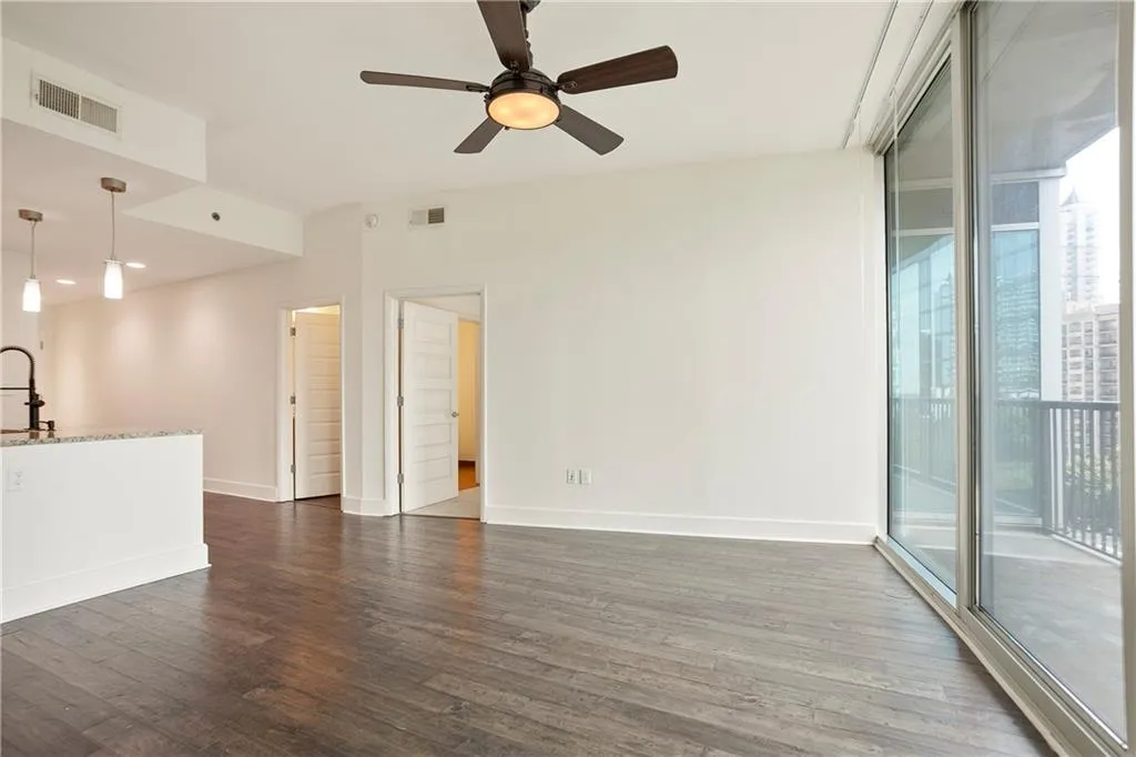 Unfurnished living room featuring dark wood-style floors and a ceiling fan