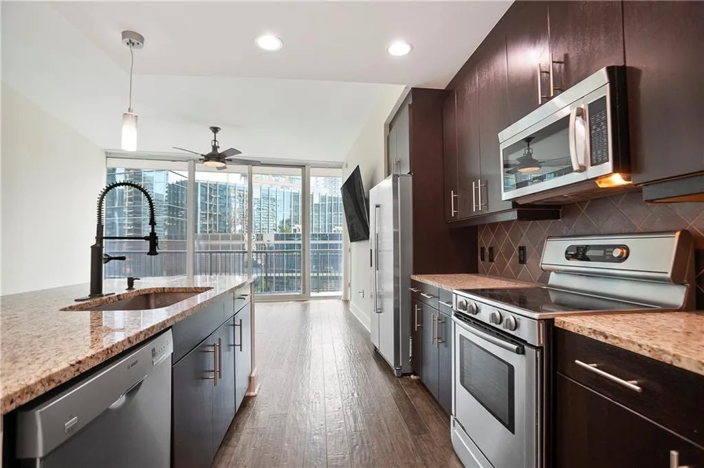 Kitchen with stainless steel appliances, tasteful backsplash, a ceiling fan, dark wood-type flooring, and dark brown cabinetry