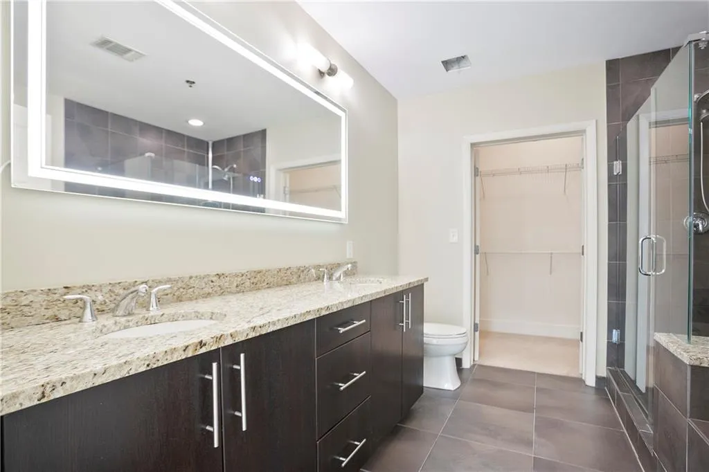 Full bathroom featuring a stall shower, double vanity, tile patterned flooring, and a spacious closet