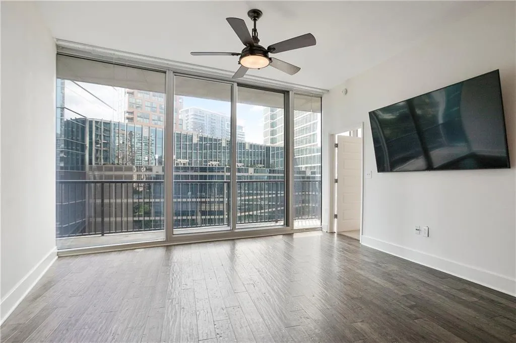 Spare room with expansive windows, wood finished floors, and a ceiling fan