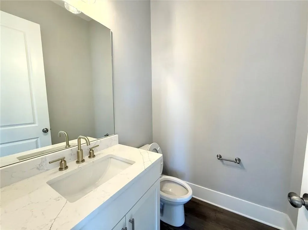 Bathroom featuring vanity, wood finished floors, toilet, and baseboards