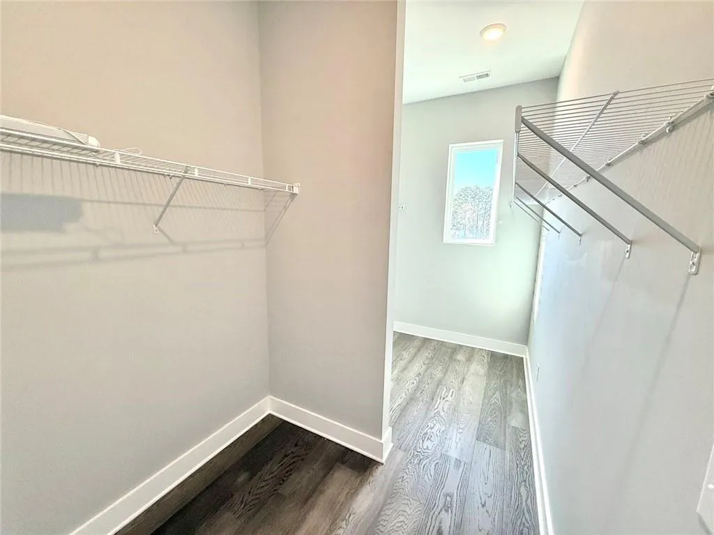 Spacious closet featuring dark wood finished floors and visible vents