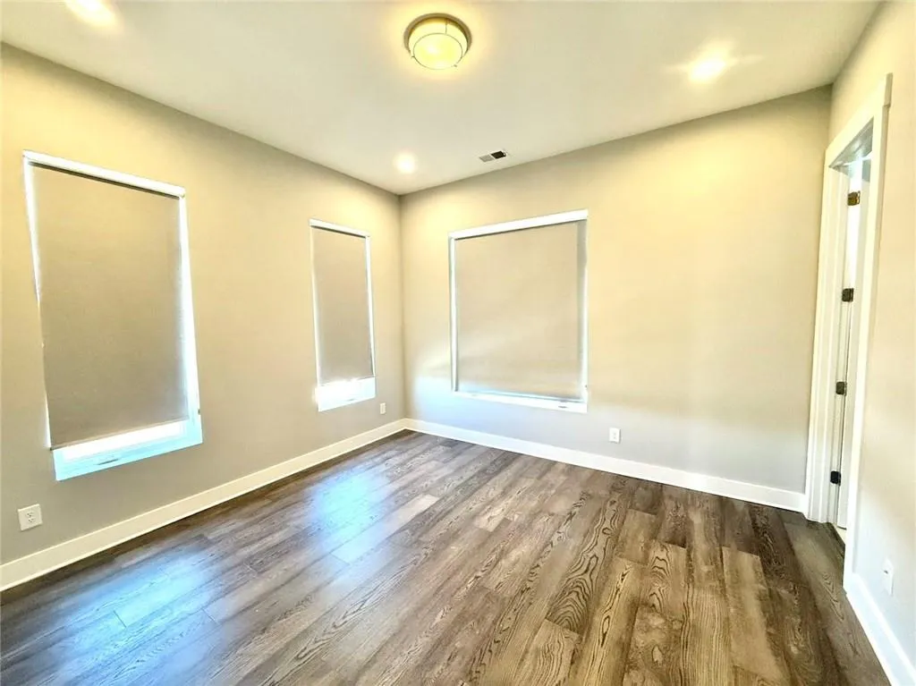 Spare room with dark wood-type flooring, visible vents, and baseboards