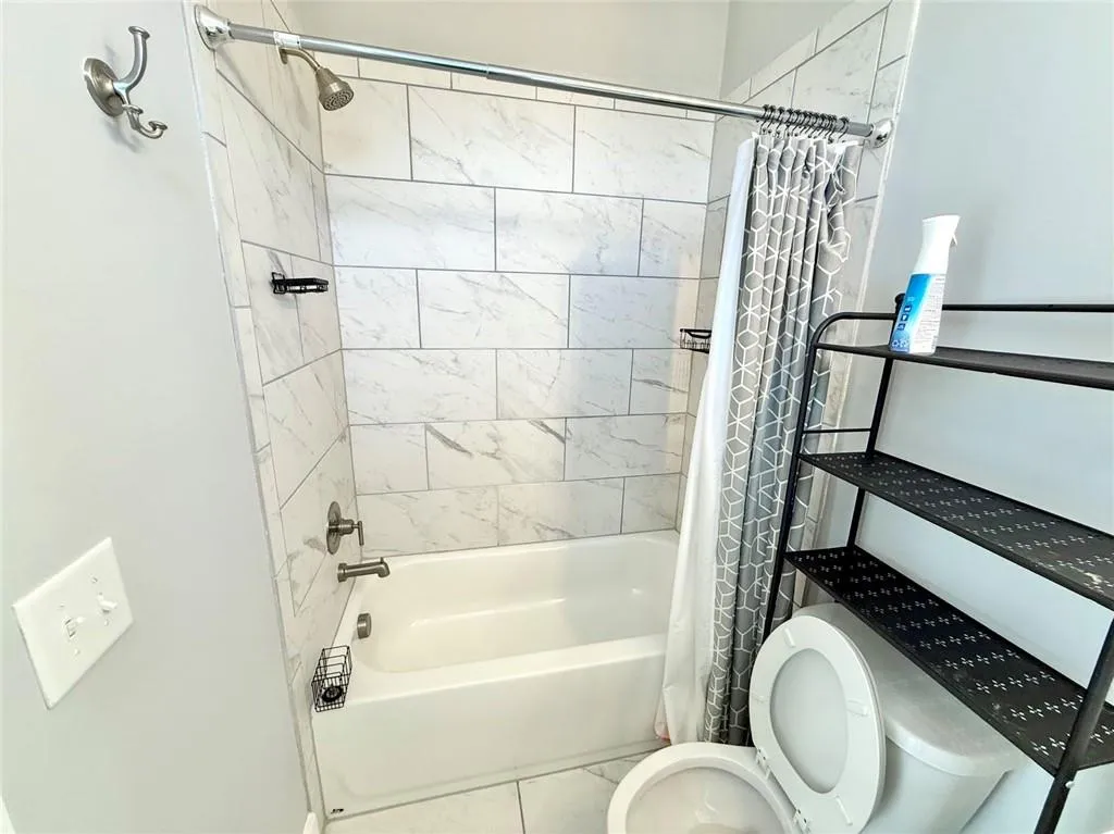 Bathroom featuring toilet and shower / bath combo with shower curtain