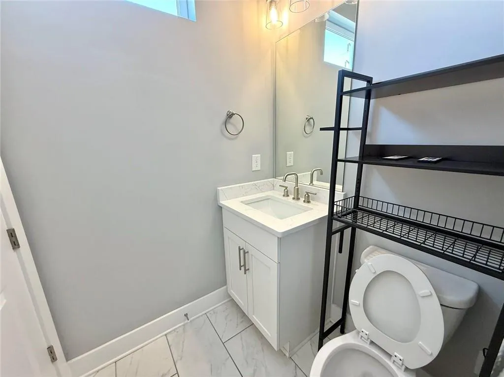 Bathroom with marble finish floor, vanity, toilet, and baseboards