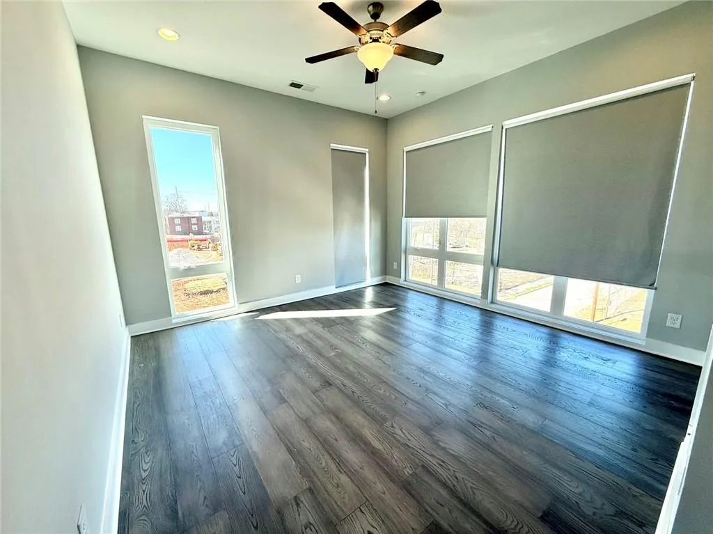 Empty room featuring dark wood-type flooring, visible vents, and baseboards