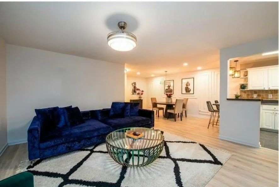 Living room with light hardwood / wood-style floors and a notable chandelier