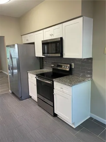 Kitchen with stainless steel electric range oven, tasteful backsplash, and white cabinetry