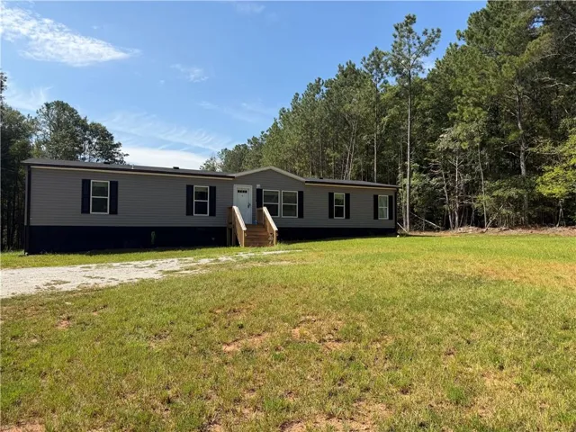 Siding exterior with contrasting foundation, wood entrance steps, and a gravel driveway