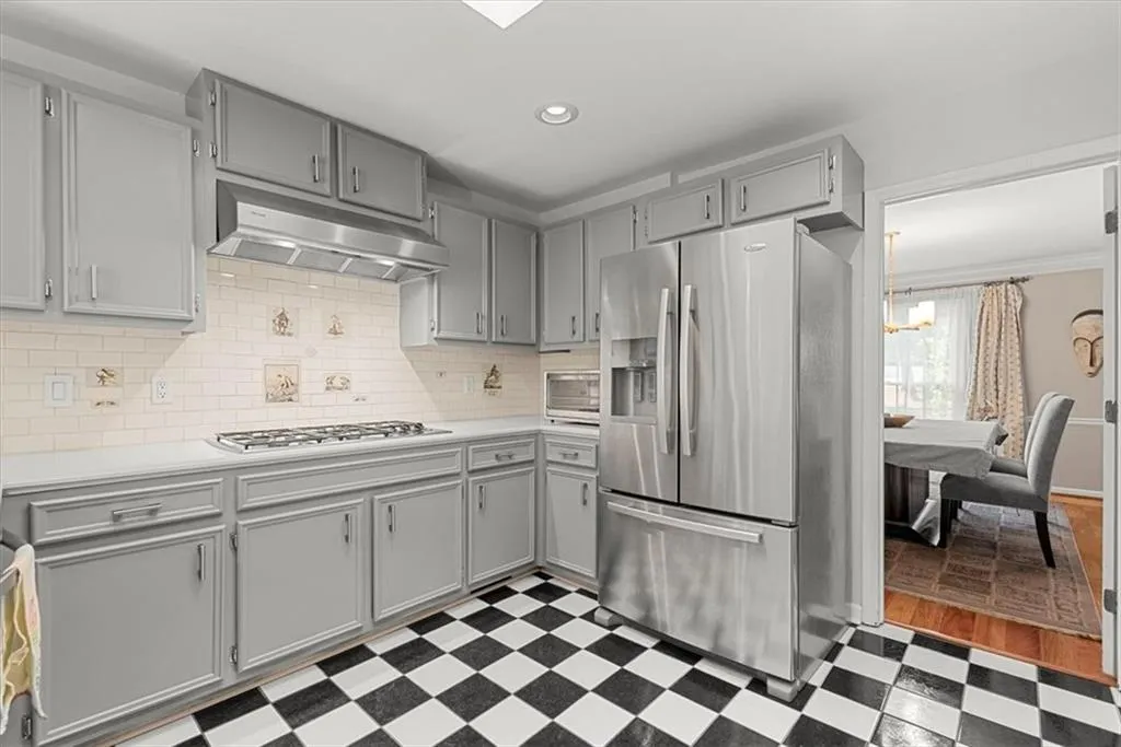 Kitchen featuring tile floors, backsplash, gray cabinetry, ornamental molding, and appliances with stainless steel finishes