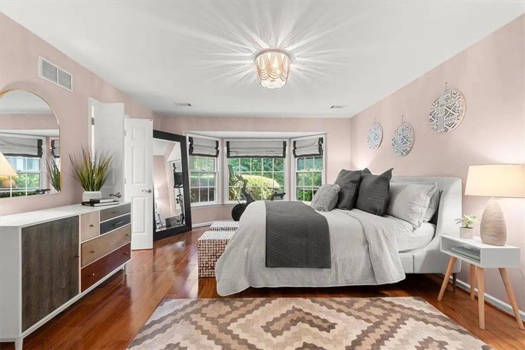 Primary Bedroom with hardwood floors, bay window