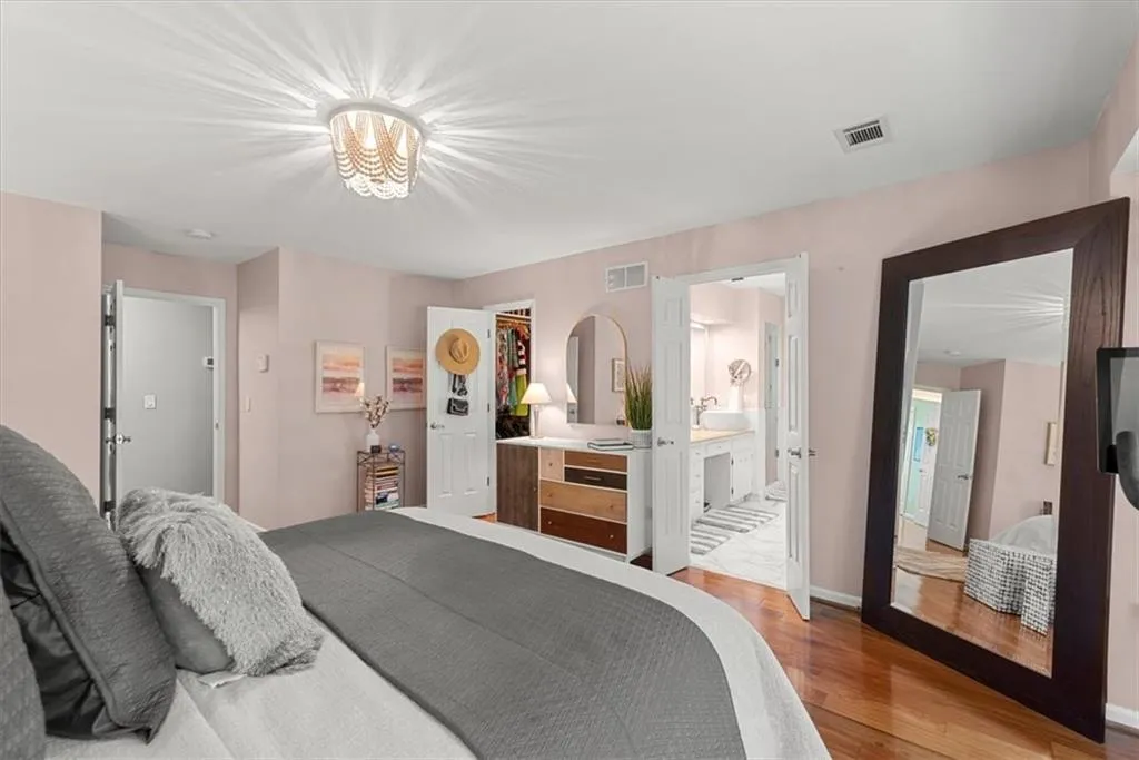 Primary Bedroom featuring a walk-in closet, ensuite bathroom, hardwood flooring