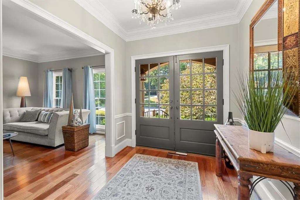 Entrance foyer with a notable chandelier, ornamental molding, hardwood flooring, and french doors
