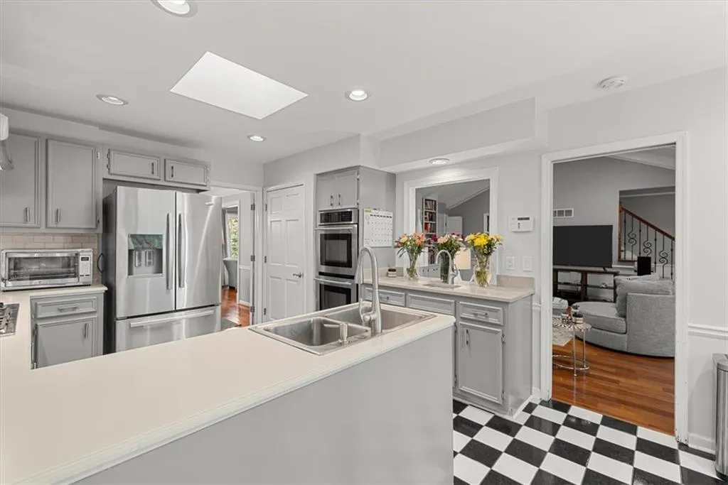 Kitchen featuring appliances with stainless steel finishes, a skylight, light tile floors, and gray cabinets
