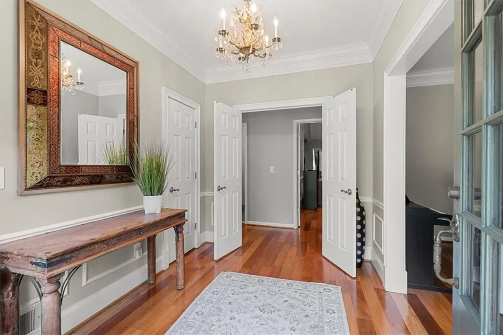 Hallway featuring ornamental molding, a chandelier, and hardwood flooring