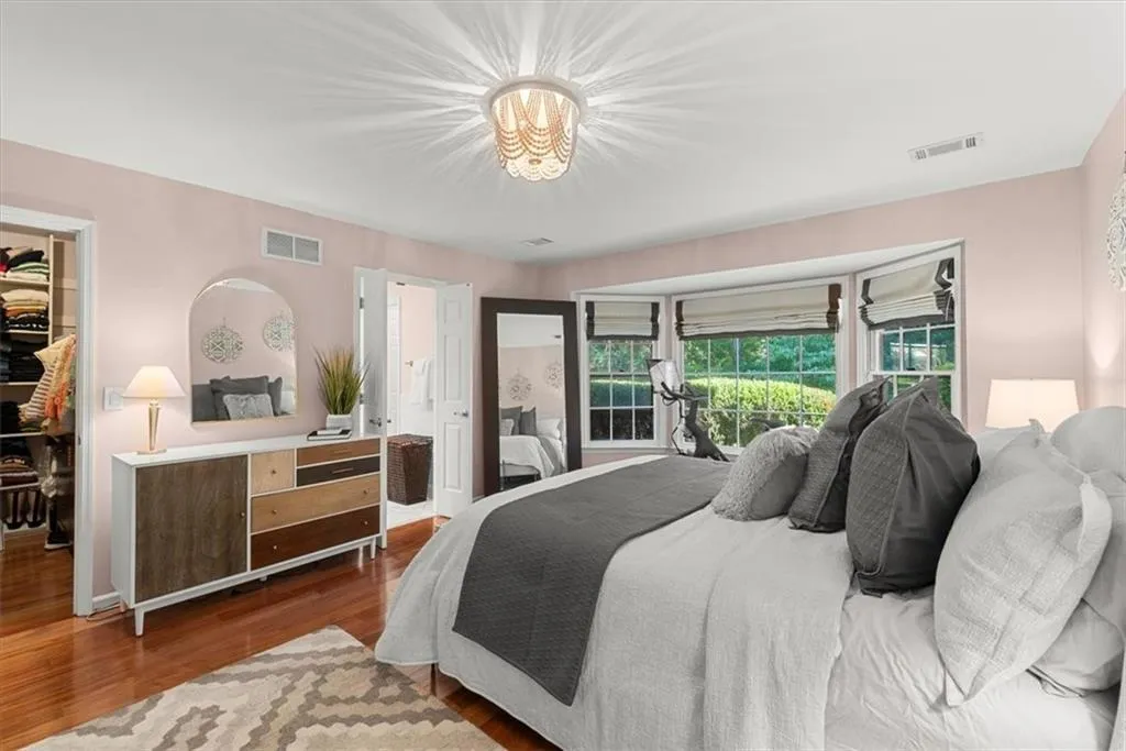 Primary Bedroom with a walk-in closet and hardwood flooring