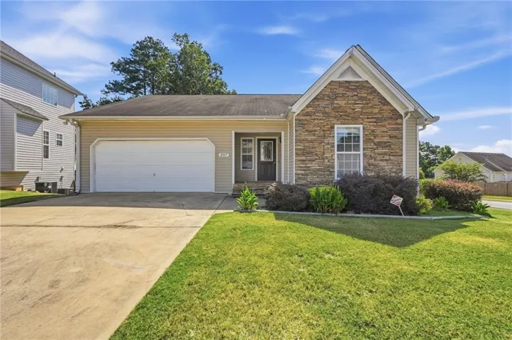 Exterior featuring stone accents, vinyl siding, a gabled roofline, an attached garage, and a concrete driveway