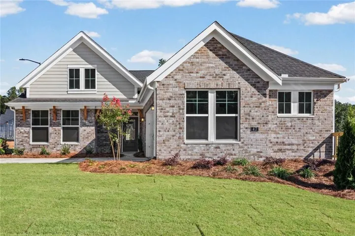 New construction featuring a dark shingle roof, multiple white-framed windows, and an attached garage