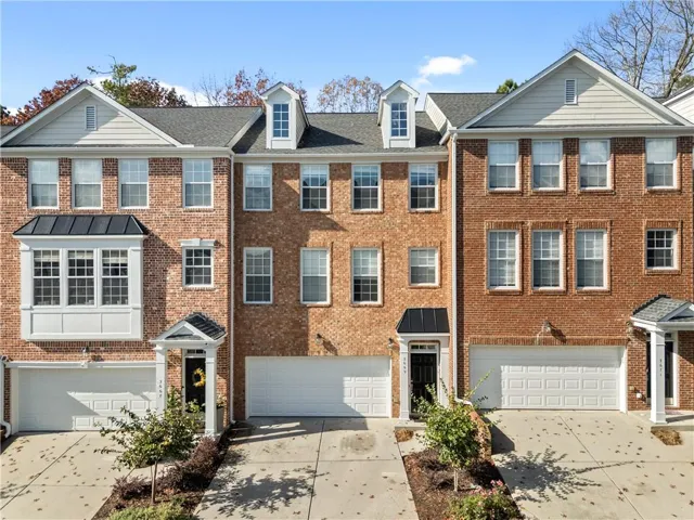 Colonial house with driveway, brick siding, and an attached garage