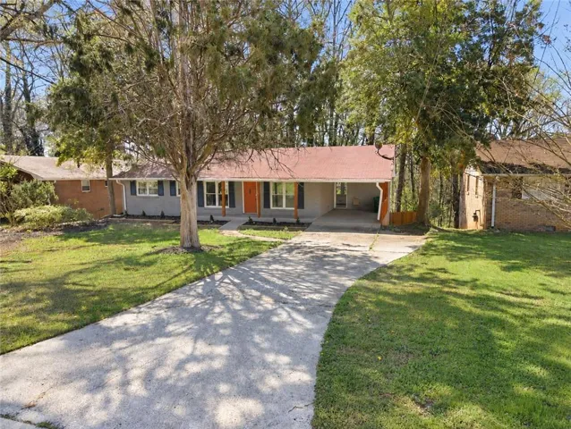 Ranch-style residence featuring a prominent orange front door, blue window shutters, and a covered carport