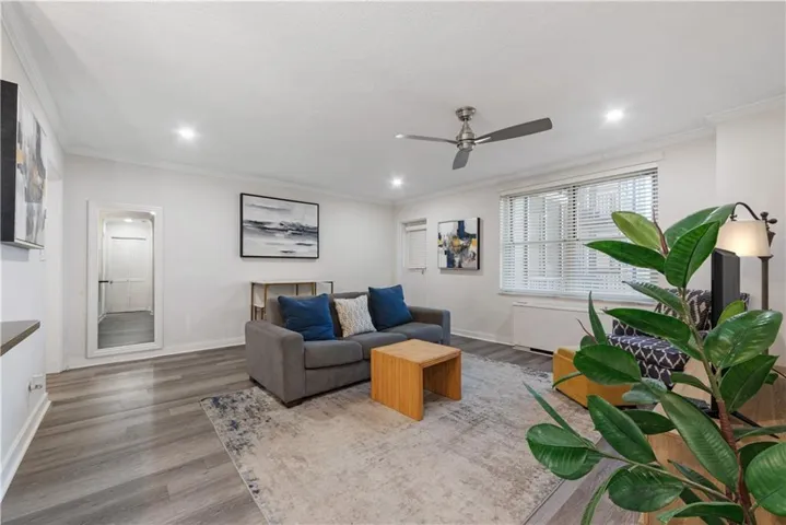 Living area with crown molding, wood finished floors, ceiling fan, and recessed lighting