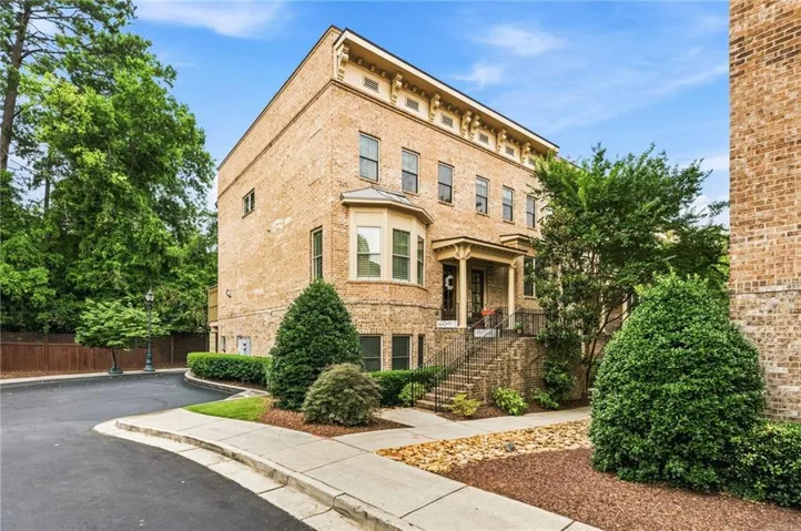 Multi-story brick facade featuring an ornate cornice, bay window, and a covered entry porch