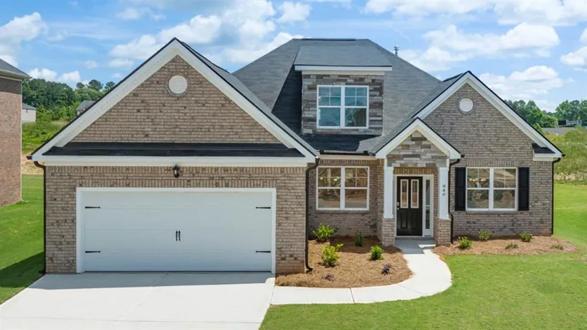 Craftsman-style home featuring brick siding, a front lawn, driveway, an attached garage, and a shingled roof