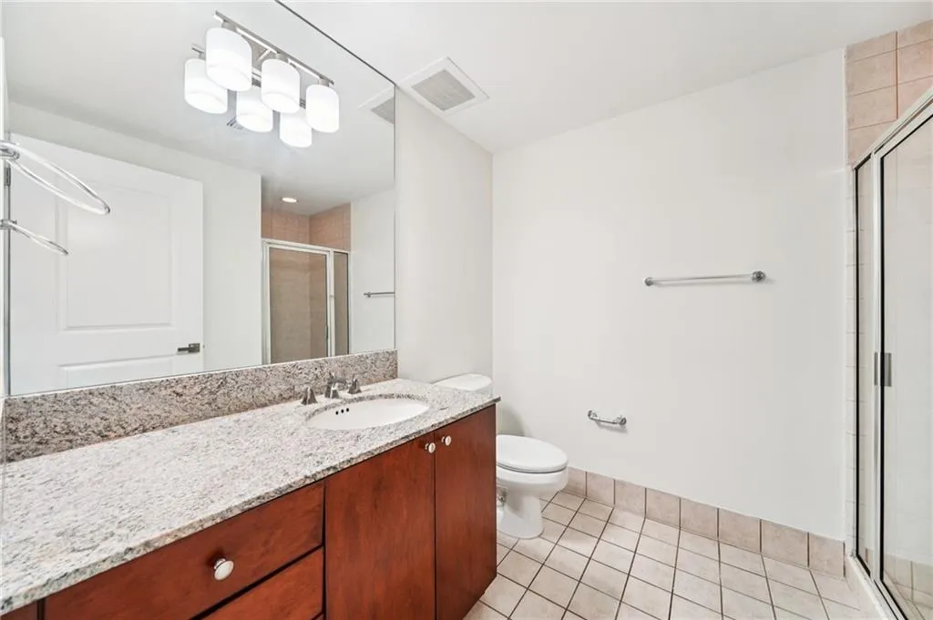 Bathroom with vanity, light tile patterned floors, and a shower stall